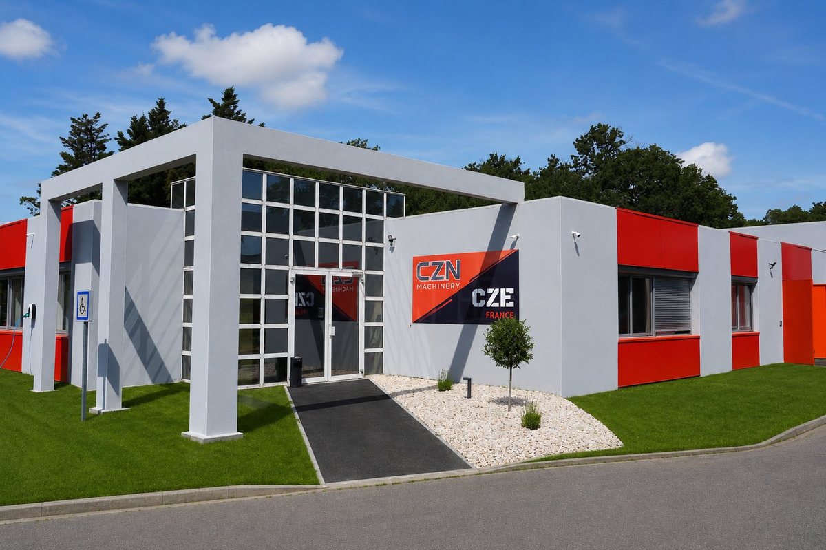 Façade des bureaux CZN Machinery près de Toulouse : bâtiment moderne gris et rouge avec enseigne CZN Machinery, entrée vitrée et borne de recharge — siège de l'importateur direct de mini-pelles et engins de chantier